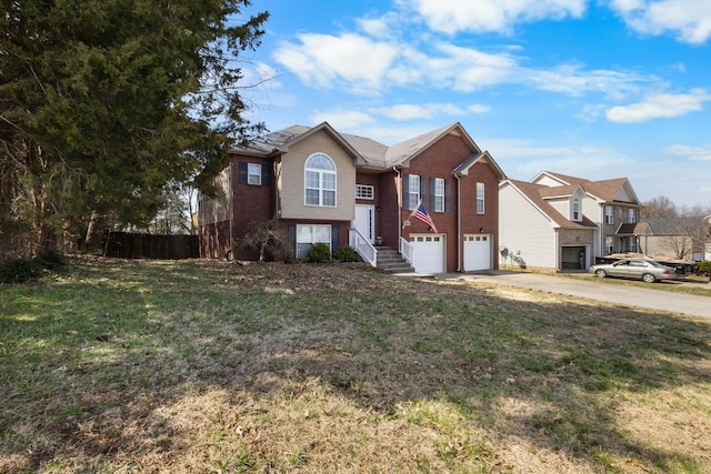 bi-level home with brick siding, fence, concrete driveway, a front yard, and an attached garage