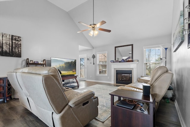 living area featuring baseboards, high vaulted ceiling, a fireplace with flush hearth, ceiling fan, and dark wood-type flooring