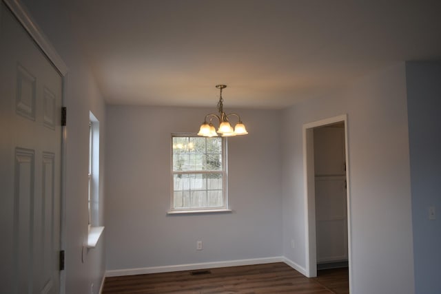 unfurnished room with dark wood finished floors, an inviting chandelier, visible vents, and baseboards