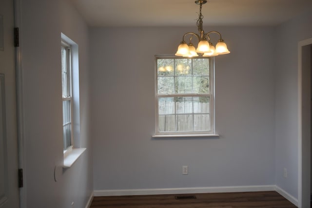 unfurnished room with visible vents, baseboards, dark wood-style flooring, and a chandelier