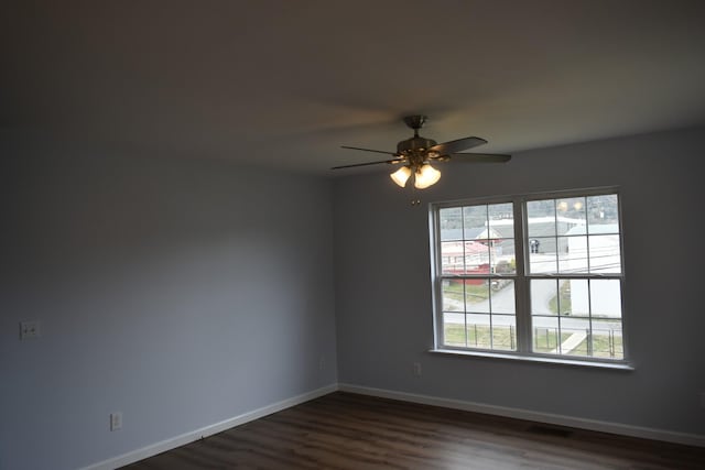 spare room with dark wood finished floors, visible vents, baseboards, and ceiling fan