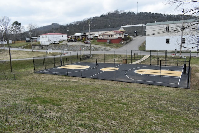 view of basketball court featuring a lawn, community basketball court, and fence