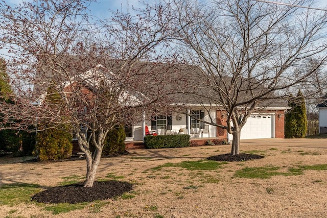 view of front of home with driveway, covered porch, a front lawn, a garage, and brick siding