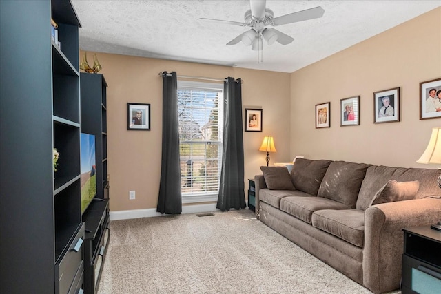 living area with a textured ceiling, light colored carpet, visible vents, and ceiling fan