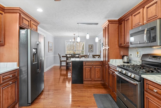 kitchen with brown cabinetry, a peninsula, stainless steel appliances, crown molding, and light wood-type flooring