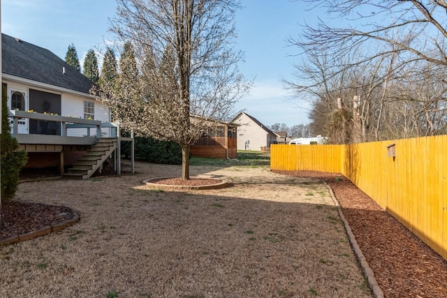 view of yard featuring a wooden deck, stairs, and fence