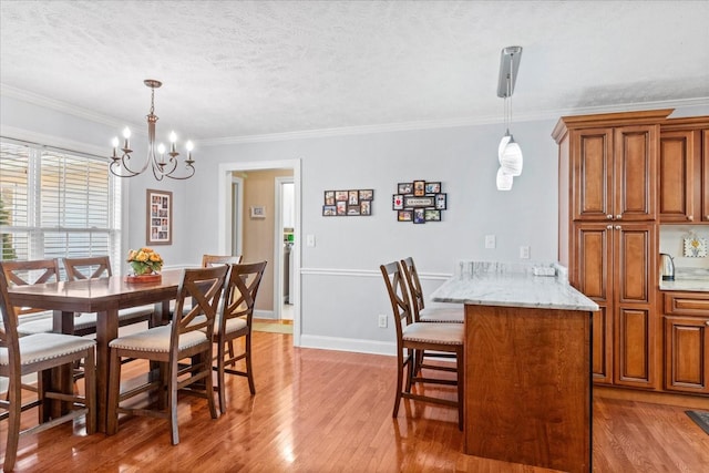 dining area featuring baseboards, light wood finished floors, a textured ceiling, crown molding, and a chandelier