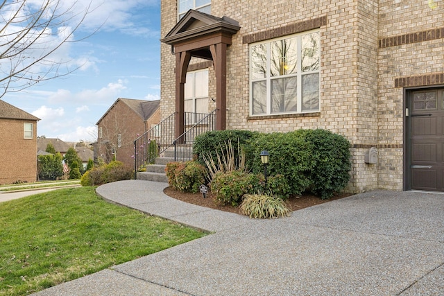 view of exterior entry featuring a yard and brick siding