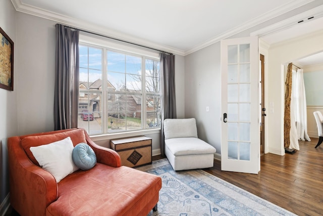 living area with baseboards, wood finished floors, and crown molding