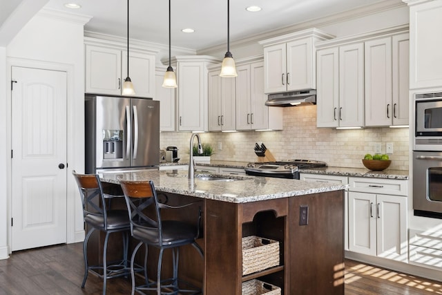 kitchen featuring an island with sink, under cabinet range hood, open shelves, stainless steel appliances, and dark wood-style flooring