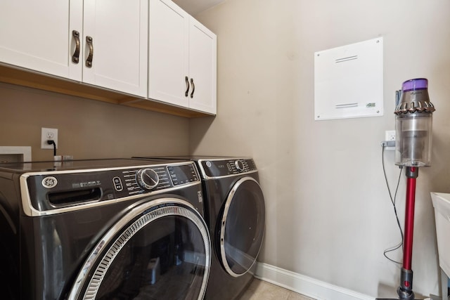 laundry room featuring washing machine and dryer, cabinet space, and baseboards