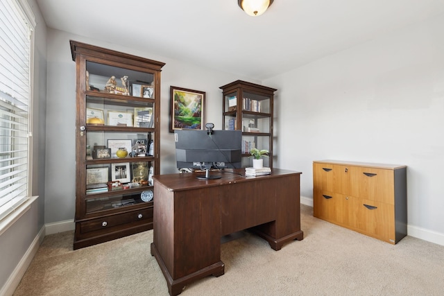 office space with baseboards and light carpet