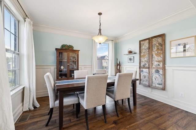 dining space featuring dark wood finished floors, crown molding, visible vents, and wainscoting