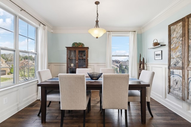 dining room featuring dark wood-style floors, a decorative wall, a wainscoted wall, and ornamental molding