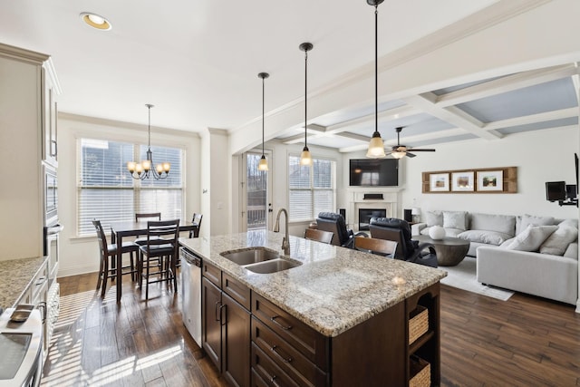 kitchen featuring coffered ceiling, stainless steel appliances, a sink, dark brown cabinetry, and a glass covered fireplace