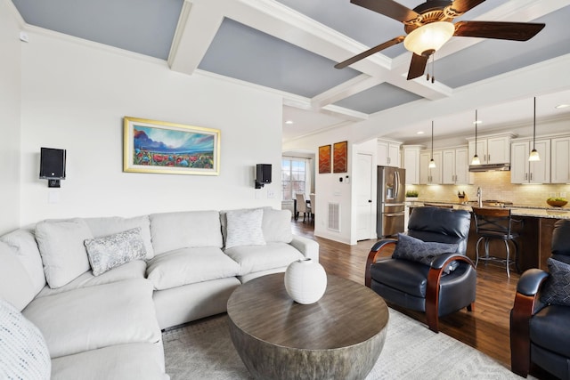 living area featuring ceiling fan, beamed ceiling, coffered ceiling, and wood finished floors