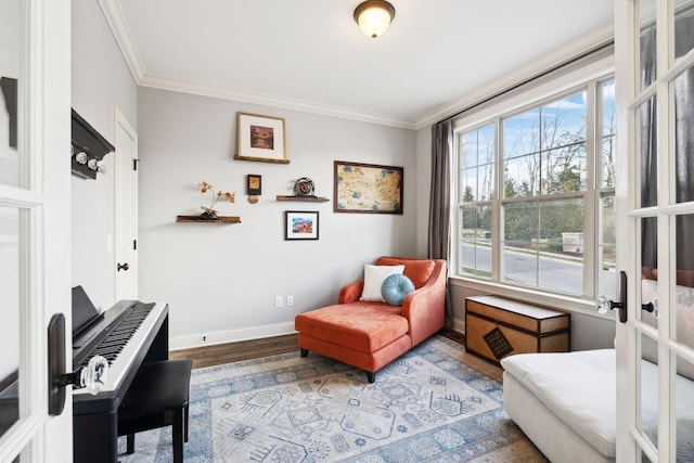 sitting room with baseboards, wood finished floors, and crown molding