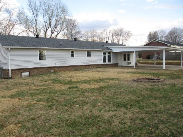 back of property featuring a yard, a patio, and an attached carport