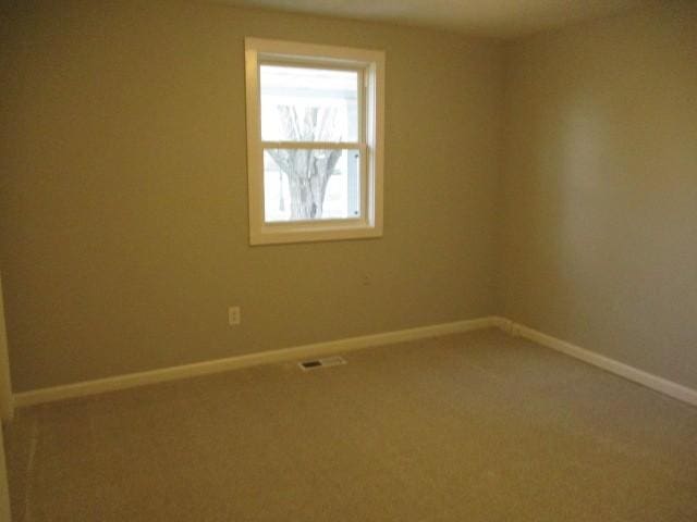 carpeted empty room featuring visible vents and baseboards