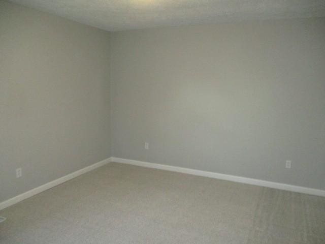 empty room with baseboards and light colored carpet