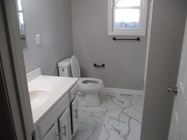 bathroom featuring visible vents, toilet, marble finish floor, baseboards, and vanity