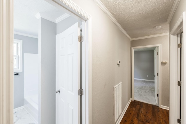 hallway featuring wood finished floors, visible vents, ornamental molding, baseboards, and a textured ceiling