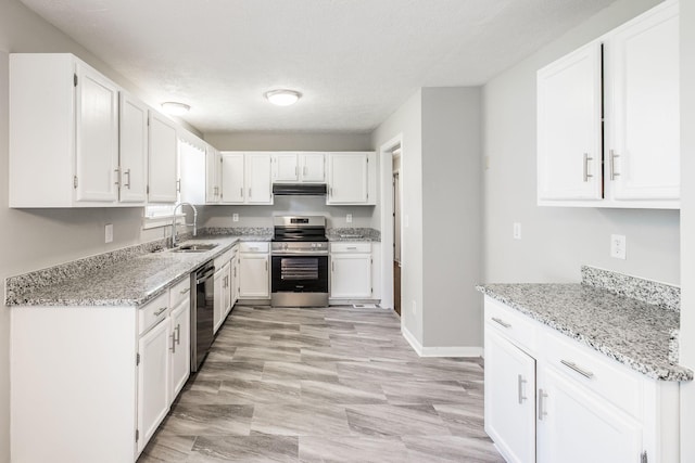 kitchen with white cabinets, stainless steel appliances, a sink, light stone counters, and under cabinet range hood