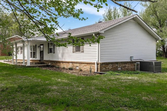 view of side of property with a lawn, central AC unit, and a shingled roof