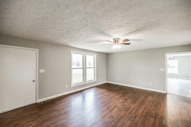 unfurnished room featuring a ceiling fan, a textured ceiling, baseboards, dark wood-type flooring, and visible vents