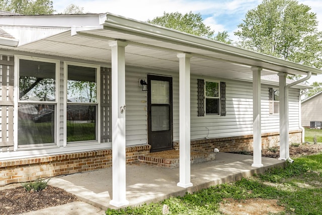 doorway to property featuring brick siding and covered porch