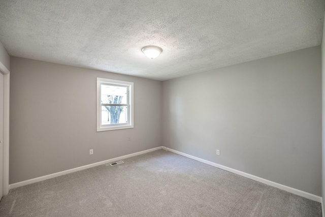 empty room featuring a textured ceiling, visible vents, carpet flooring, and baseboards