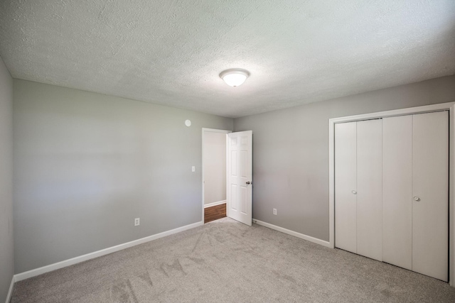 unfurnished bedroom featuring a textured ceiling, a closet, carpet flooring, and baseboards