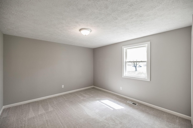 unfurnished room with baseboards, visible vents, a textured ceiling, and carpet flooring