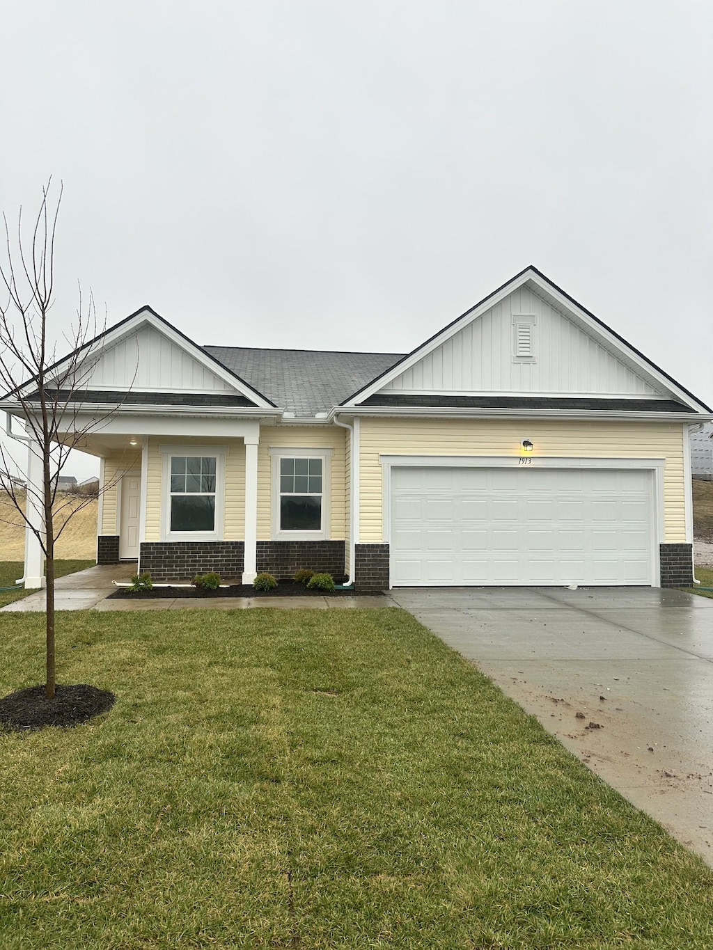 view of front facade with central AC unit, driveway, a front lawn, a garage, and brick siding