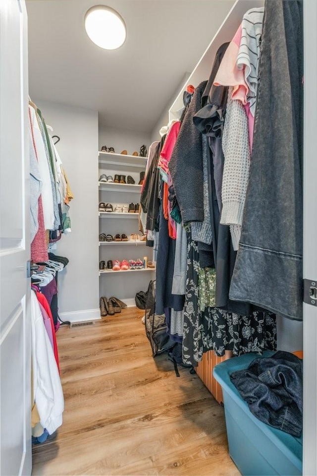 walk in closet with wood finished floors