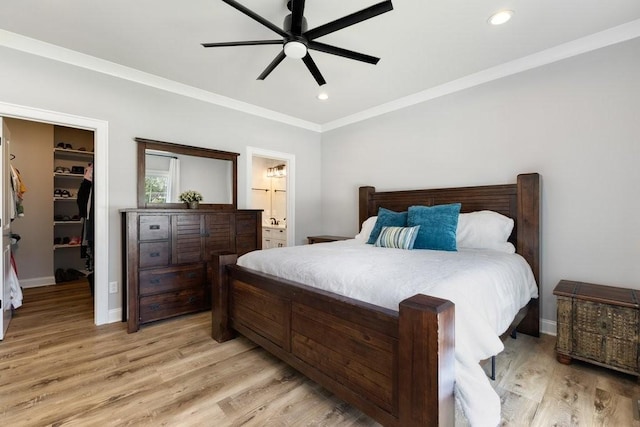 bedroom featuring a spacious closet, crown molding, recessed lighting, light wood-style flooring, and a closet