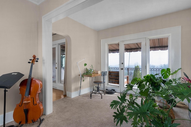 interior space featuring french doors, arched walkways, carpet, and baseboards