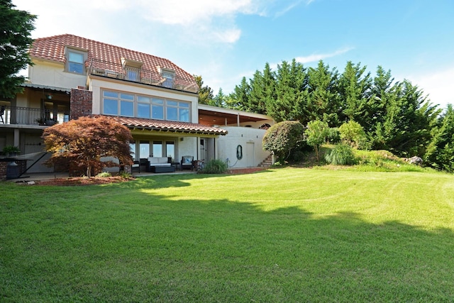 rear view of house featuring an outdoor living space, stucco siding, a lawn, and a tile roof