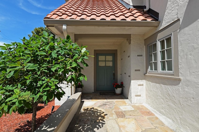 property entrance with a tiled roof and stucco siding