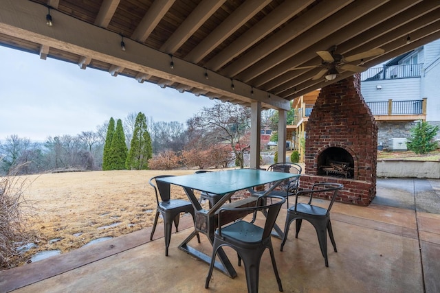 view of patio featuring ceiling fan, outdoor dining space, and an outdoor brick fireplace