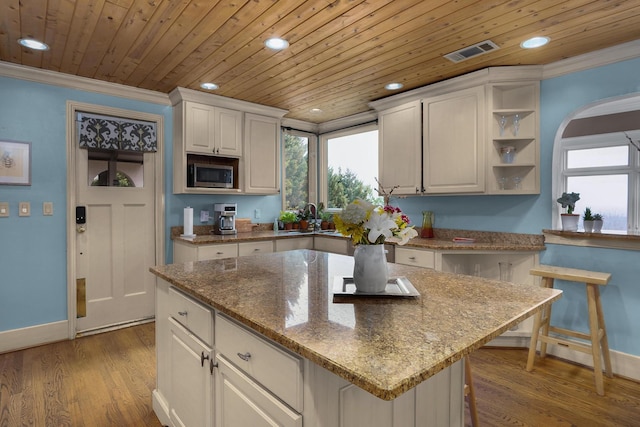 kitchen with ornamental molding, stainless steel microwave, wood finished floors, recessed lighting, and wood ceiling