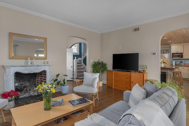 living room with visible vents, wood finished floors, stairway, arched walkways, and a fireplace