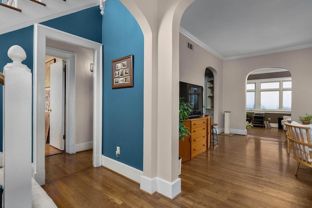 hall with crown molding, wood finished floors, visible vents, and baseboards