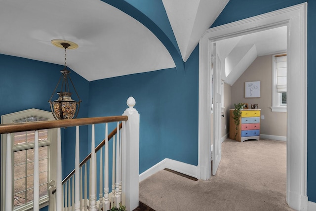 hallway with vaulted ceiling, an upstairs landing, baseboards, and carpet floors