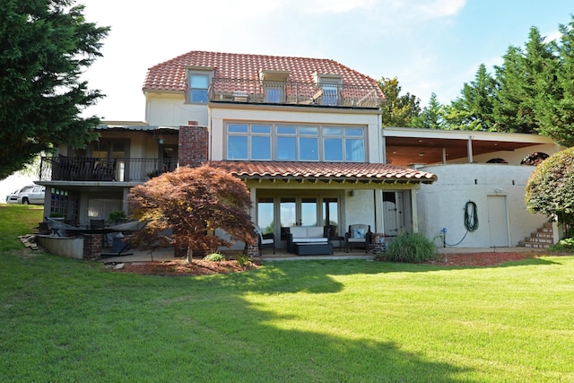 rear view of house with stucco siding, a lawn, a tile roof, an outdoor living space, and a patio