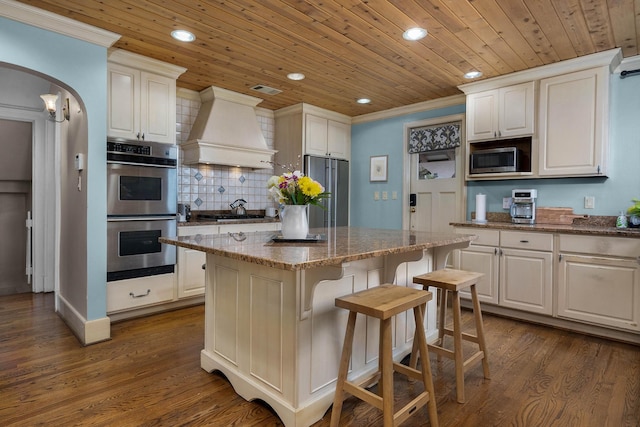 kitchen featuring stainless steel appliances, arched walkways, crown molding, custom exhaust hood, and wood ceiling