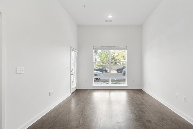 spare room featuring visible vents, baseboards, and dark wood finished floors