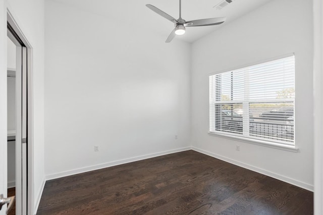 empty room featuring dark wood-style floors, visible vents, baseboards, and a ceiling fan