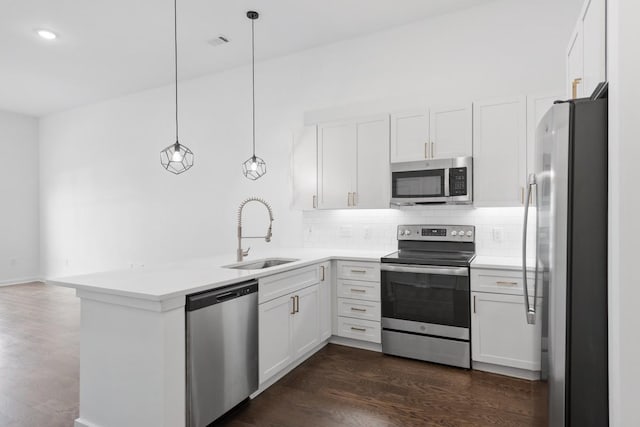 kitchen featuring decorative backsplash, a peninsula, white cabinets, stainless steel appliances, and a sink