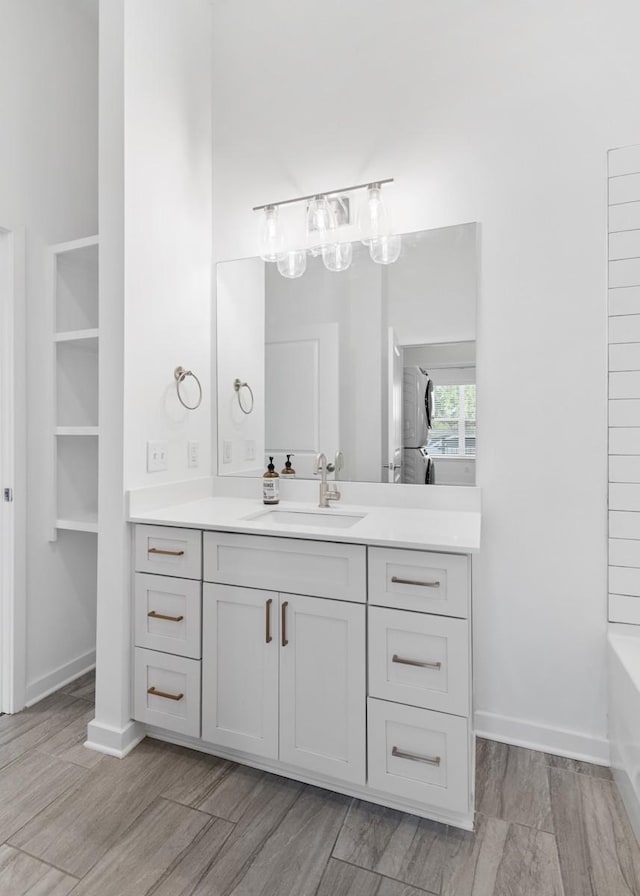 full bath featuring baseboards, a tub to relax in, and vanity